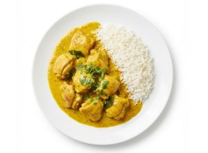 Plato de pollo al curry con arroz basmati blanco servido en un plato blanco